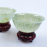 A pair of jade bowls on carved wood stands, 4" across