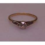 An unmarked gold solitaire diamond ring with diamond set shoulders