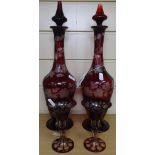 A pair of ruby glass decanters and stoppers, with engraved grapevine decoration, height 38cm, and