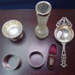 A silver tea strainer, a bowl, 2 napkin rings, a silver thimble, cased, and a silver-topped bud vase