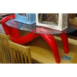 A modernist oval glass-top coffee table, on stylised red plastic base, L125cm