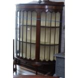 A 1930s mahogany bow-front glass display cabinet, raised on cabriole legs with claw and ball feet,