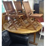 A large circular teak garden table, together with a set of 4 matching folding chairs, and a