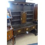 A 1920s oak 2-section dresser, having a boarded open plate rack with panelled cupboard, base