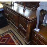 An Arts and Crafts oak sideboard, with raised panelled back, fitted drawers and cupboards, with