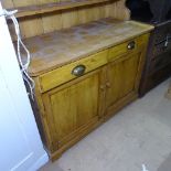 A polished pine dresser, with glazed cupboards, and drawers and panelled cupboards under on plinth