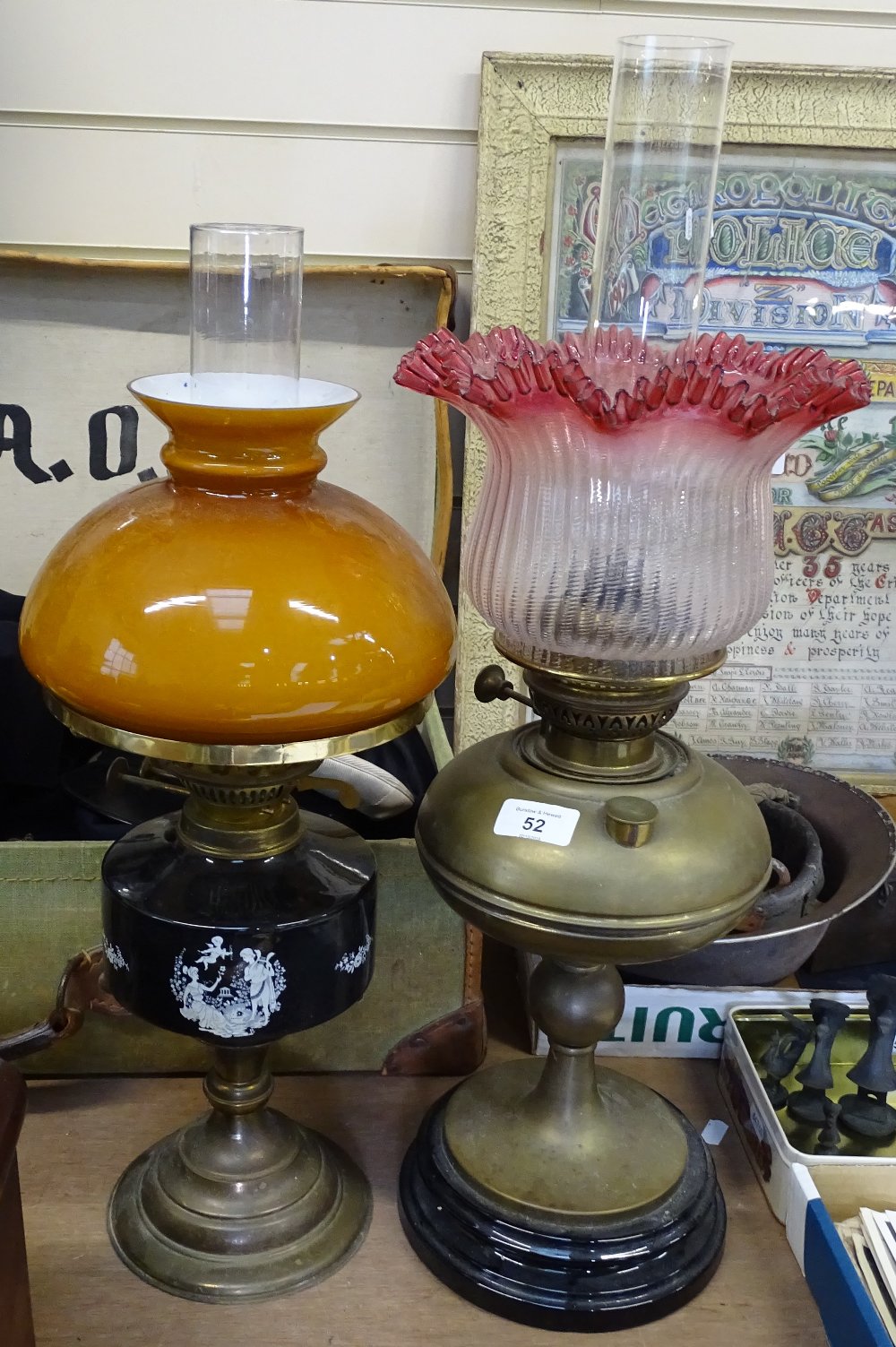 A brass oil lamp with a cranberry glass shade and chimney, height 61cm, and another oil lamp
