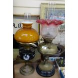 A brass oil lamp with a cranberry glass shade and chimney, height 61cm, and another oil lamp