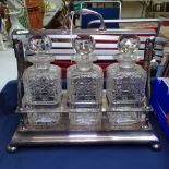 A silver plated 3-bottle tantalus, complete with decanters, on bun feet, unmarked
