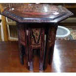 A black lacquered and painted octagonal table on folding base