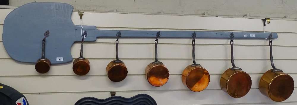 A set of 7 graduated copper pans and pan rack