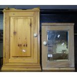 A small pine cabinet with mirrored door, and a hanging pine cabinet with panelled door