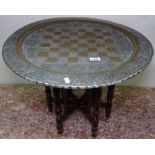 An Eastern engraved brass-top table on folding base, W57cm