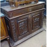 A Breton oak side cabinet, with single and figural carved fielded panel doors under, on bun feet