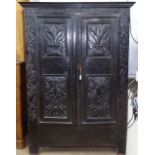 A 17th century joined oak hall cupboard, having 2 tulip-carved fielded panelled doors, and leaf