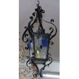 A scrolled wrought-iron hanging lantern, with leadlight glazed panels