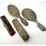 An Indian white metal embossed 4-piece dressing table brush and mirror set
