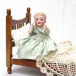 Antique German porcelain-headed doll, 27cm, with original clothes, and a doll's bed