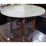 An Eastern engraved brass-top table on folding base