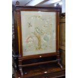 A late Victorian carved mahogany-framed firescreen, with inset needlework panel behind glass, height
