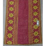A long red ground Turkish runner with symmetrical pattern, 8.3m x 65cm