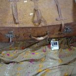 A leather suitcase and an embroidered throw