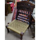 A decorative carved hardwood folding chair with woven seat