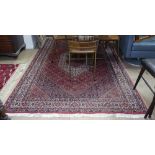 A red ground Iranian wool carpet, symmetrical pattern and border, 254cm x 160cm