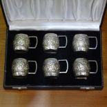 A cased set of 6 sterling silver miniature tankards with embossed decoration