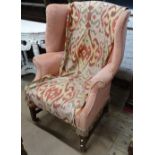 An early 20th century upholstered wingback armchair, on mahogany cross H-shaped stretcher and fluted