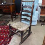 An Antique oak ladder-back rocking chair with rush-seat