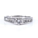 A platinum solitaire diamond ring, with channel set diamond shoulders, central stone approx 0.