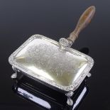 A rectangular silver silent butler, with armorial decoration and hoof feet, with turned wood handle,