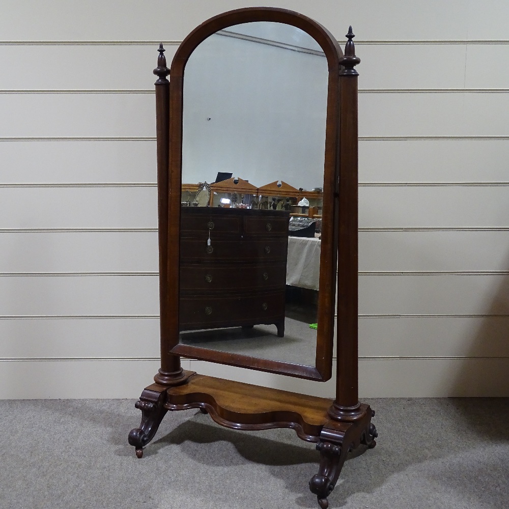 A Victorian mahogany arch-top cheval mirror, with turned tapered columns and carved base, mirror