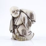 A Japanese Meiji period ivory netsuke, in the form of a man carrying a sack, height 4cm