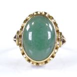 An unmarked gold oval green stone dress ring, with raised pierced bridge and shoulders, setting