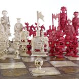 A 19th century Chinese carved red and white stained ivory chess set, with puzzle ball bases, King