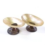 A pair of early 20th century mother-of-pearl shell table salts, on hallmarked silver bases,