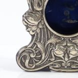 An Edwardian Art Nouveau silver-fronted watch stand, with relief embossed stylised floral decoration
