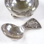 An Arts and Crafts silver caddy spoon and bowl, with pierced stylised floral handle, unmarked but