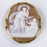 A large oval relief carved cameo shell panel brooch, depicting Cupid and 2 Classical ladies, in