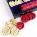 A set of Chinese/Cantonese half-stained ivory draughts pieces, decorated with figures, diameter