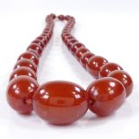 A string of graduated cherry red amber beads, containing 44 beads, largest measures 31.4mm x 23.9mm,