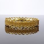 A 22ct gold circular hinged bangle, with wave central band and screw down lock, band width 10.8mm,