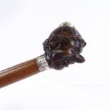 A walking stick with a carved wood handle in the form of a boy's head, unmarked silver mounts