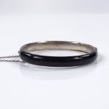 A silver black enamel and split-pearl hinged mourning bangle, with central pearl within a