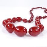 A string of graduated cherry red amber beads, with 54 beads, largest measures 34.9mm x 27.1mm, 144g