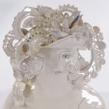 A Studio porcelain bust of a woman, painted decoration and feathered hat, maker's initials MG on