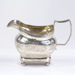 A George III silver cream jug, of bulbous form, with reeded rim and bright-cut floral decoration,
