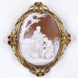 A large relief carved cameo brooch, depicting baptism near a village, in unmarked gold frame,